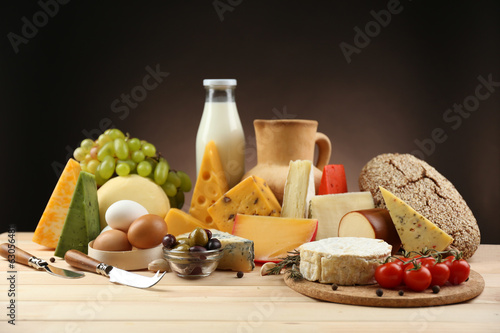 Tasty dairy products on wooden table, on dark background photo