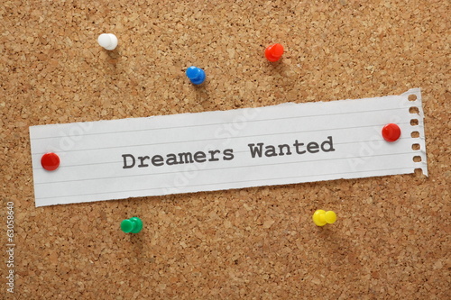 The phase Dreamers Wanted on a cork notice board