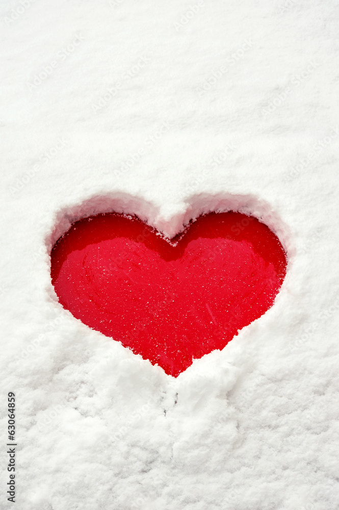 Love red heart shape in snow on red car. Close-up.