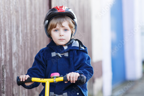 Little boy riding bicycle in village or city