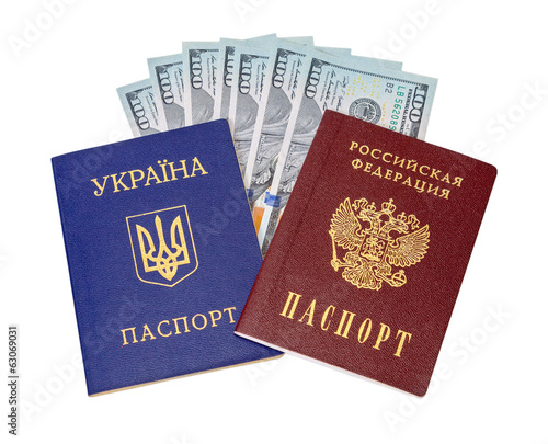 Ukrainian, Russian passports and  dollar bills over white backgr