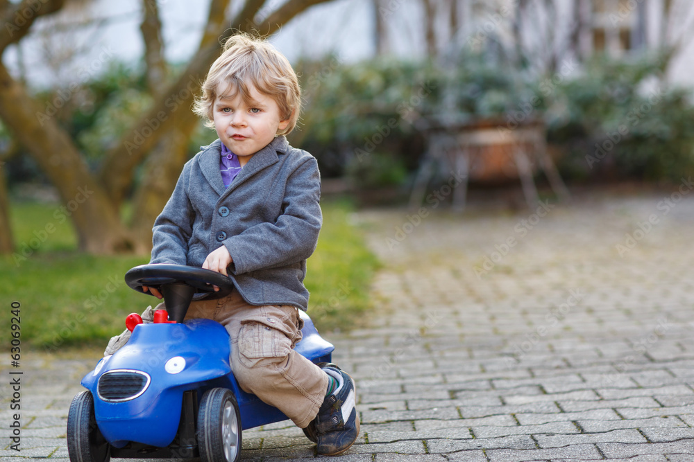 Little boy driving big toy car, outdoors