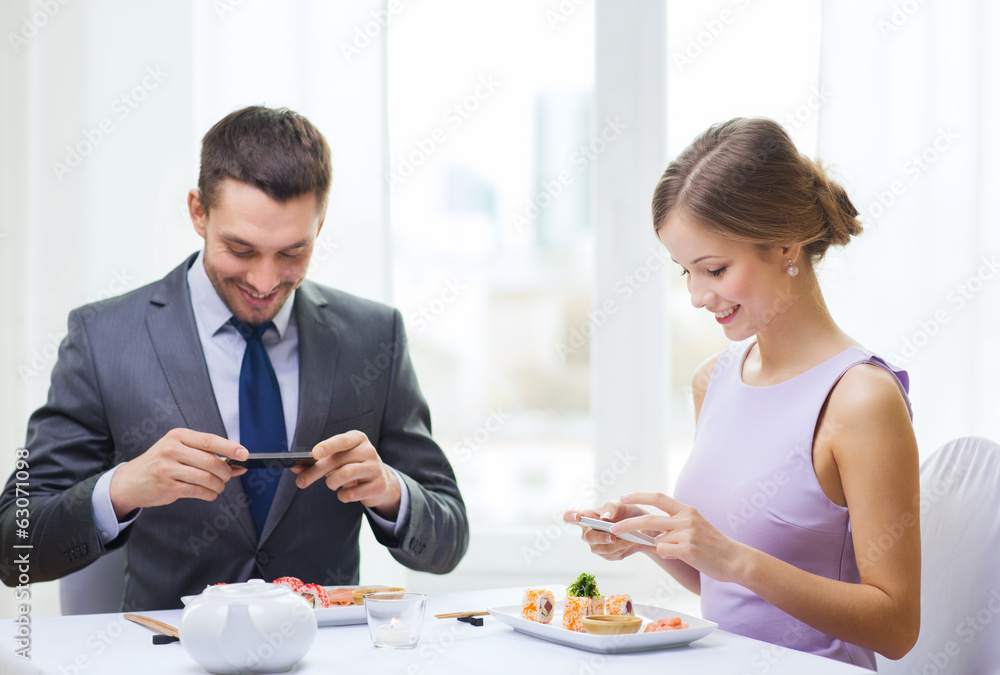 smiling couple with sushi and smartphones smiling couple with sushi and smartphones