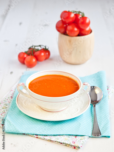 Tomato soup with tomatoes on the background on the white table,