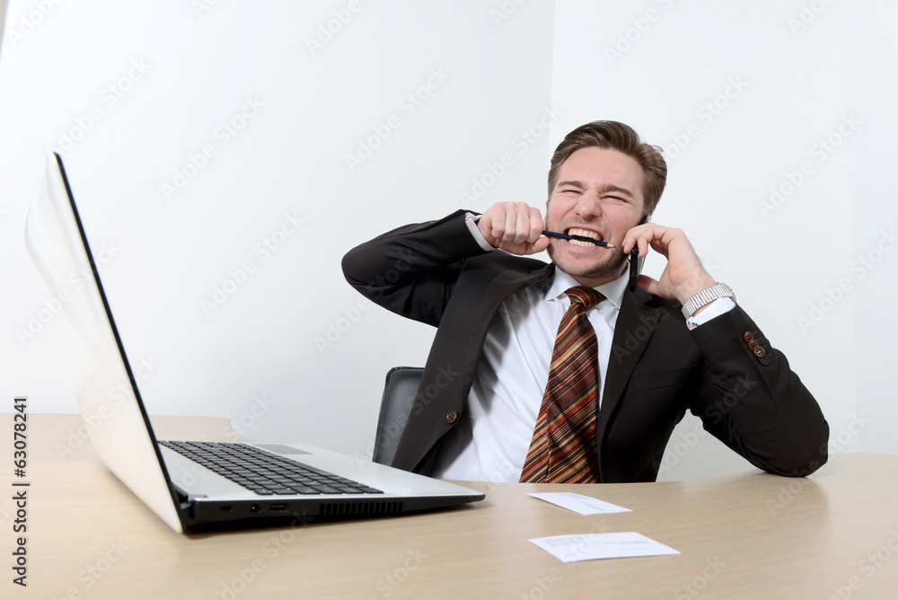 Young angry businessman breaking a pencil with teeth Young angry businessman breaking a pencil with teeth