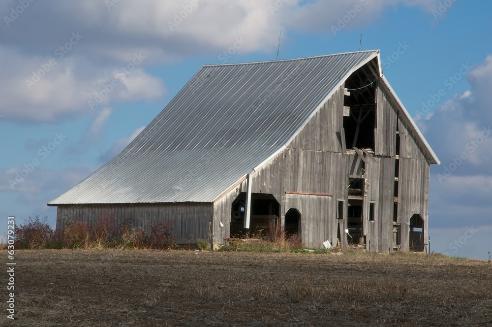 Decaying Barn in Barren Field with Blue Sky