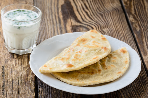 Flat bread on a plate with glass of sour milk