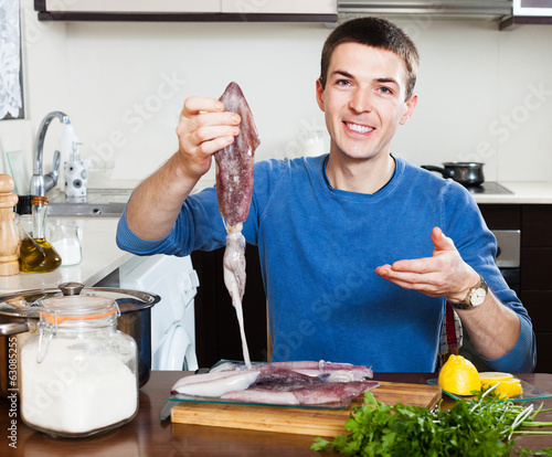 Smiling guy holding raw calamari photo