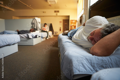 Men Lying On Beds In Homeless Shelter photo