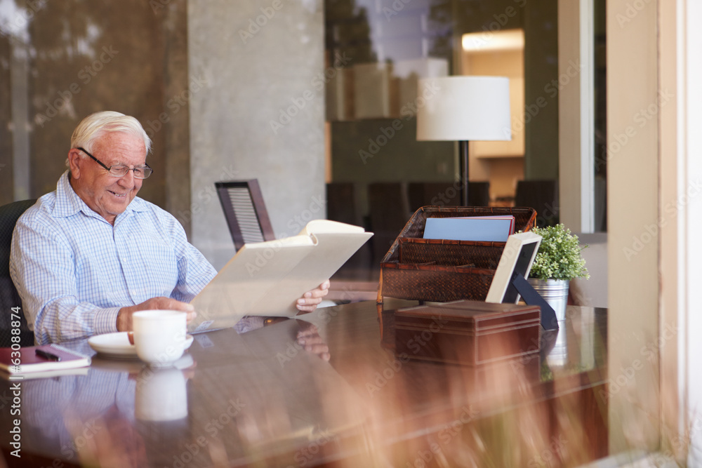 Senior Man Looking At Photo Album Through Window Senior Man Looking At Photo Album Through Window