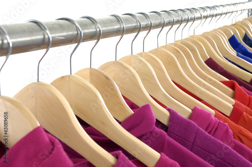 female casual clothes of different colors on wooden hangers