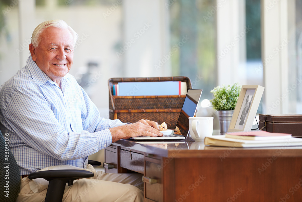 Senior Man Using Laptop On Desk At Home Senior Man Using Laptop On Desk At Home