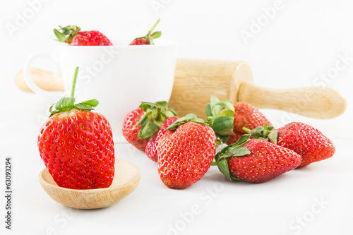 Strawberry on wood spoon and white cup with rolling pin