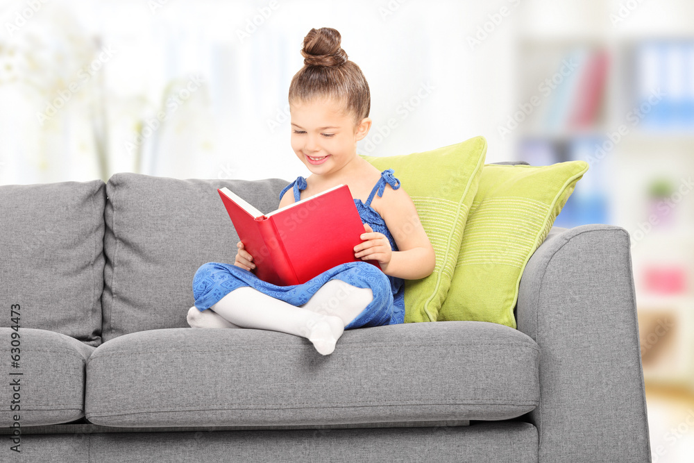 Cute little girl reading a book in the living room Cute little girl reading a book in the living room
