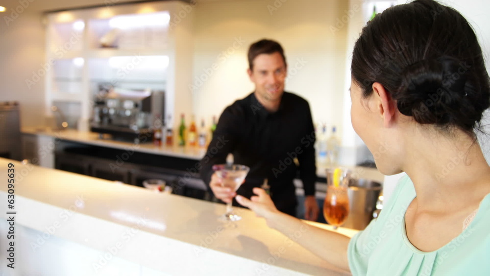 Asian woman ordering a cocktail from bartender Asian woman ordering a cocktail from bartender