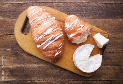Croissant and cheese on wooden board