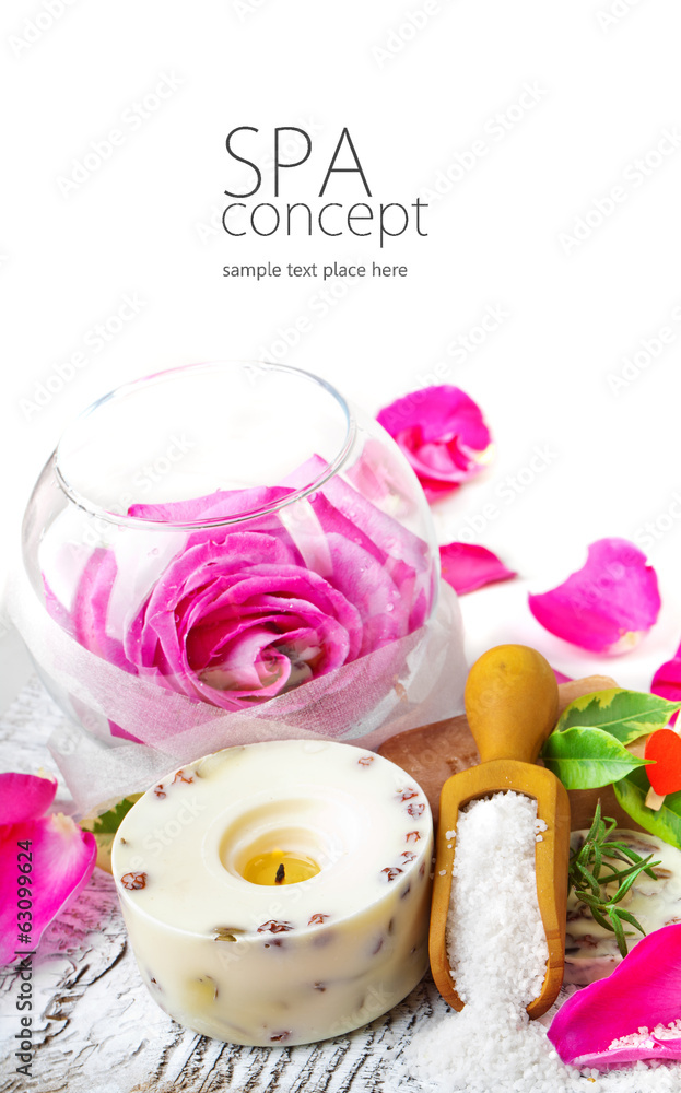 Sea salt, rose, soap and a burning candle on a white table