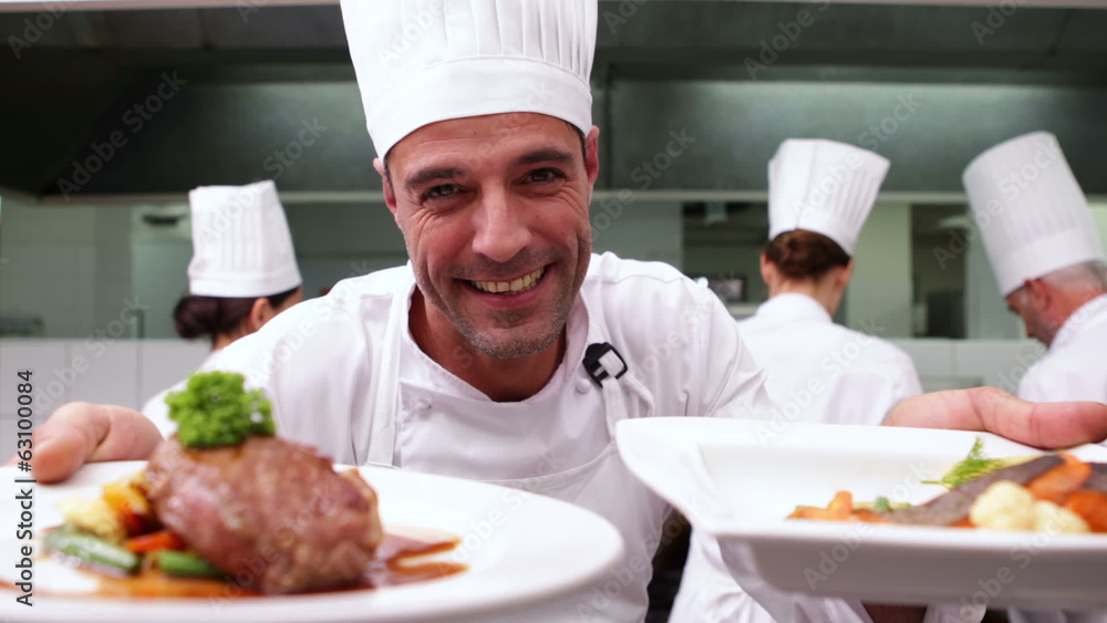 Happy chef showing two dishes to camera Happy chef showing two dishes to camera