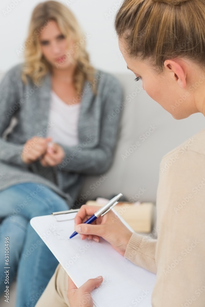Therapist writing notes on her clipboard - obrazy, fototapety, plakaty 