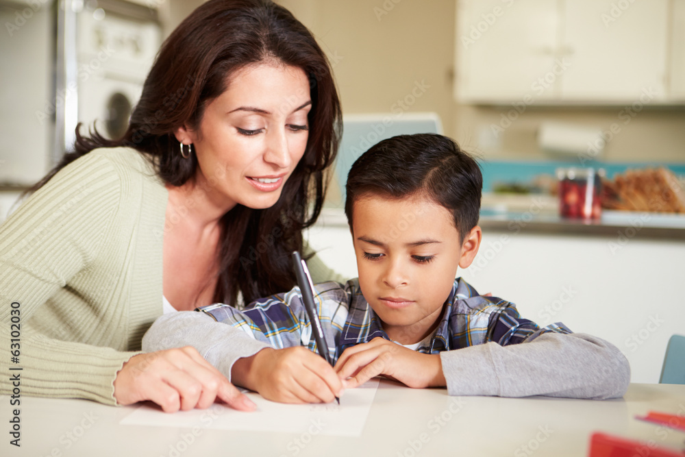 Hispanic Mother Helping Son With Homework At Table Hispanic Mother Helping Son With Homework At Table