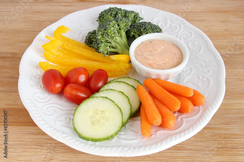 Raw vegetables on white plate with dip