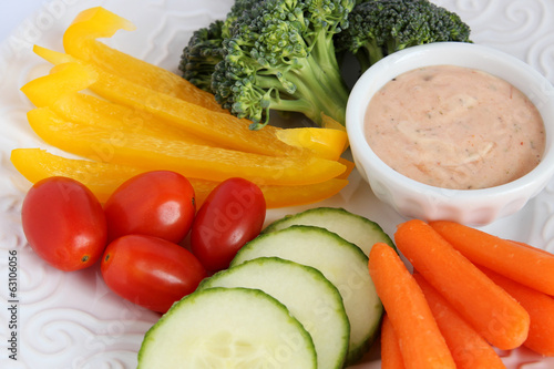 Raw vegetables on white plate with dip