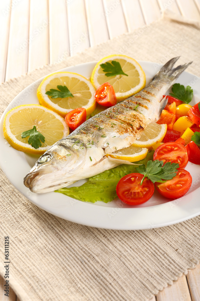 Delicious grilled fish on plate on table close-up Delicious grilled fish on plate on table close-up