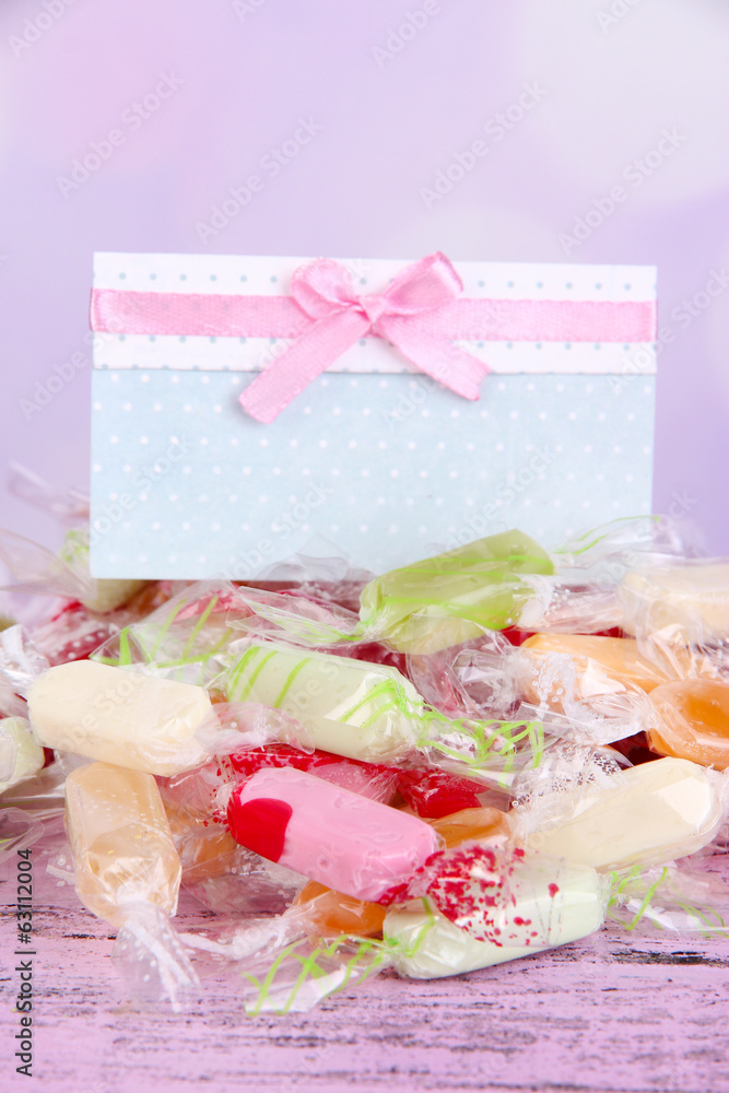 Tasty candies with card on table on bright background Tasty candies with card on table on bright background