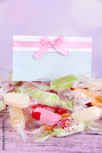Tasty candies with card on table on bright background