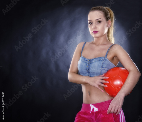 Woman with soccer ball isolated on black background © czamfir