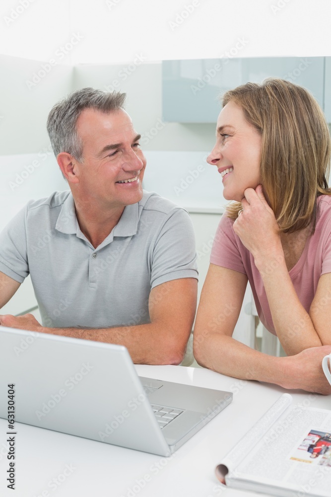 Cheerful couple using laptop in kitchen Cheerful couple using laptop in kitchen