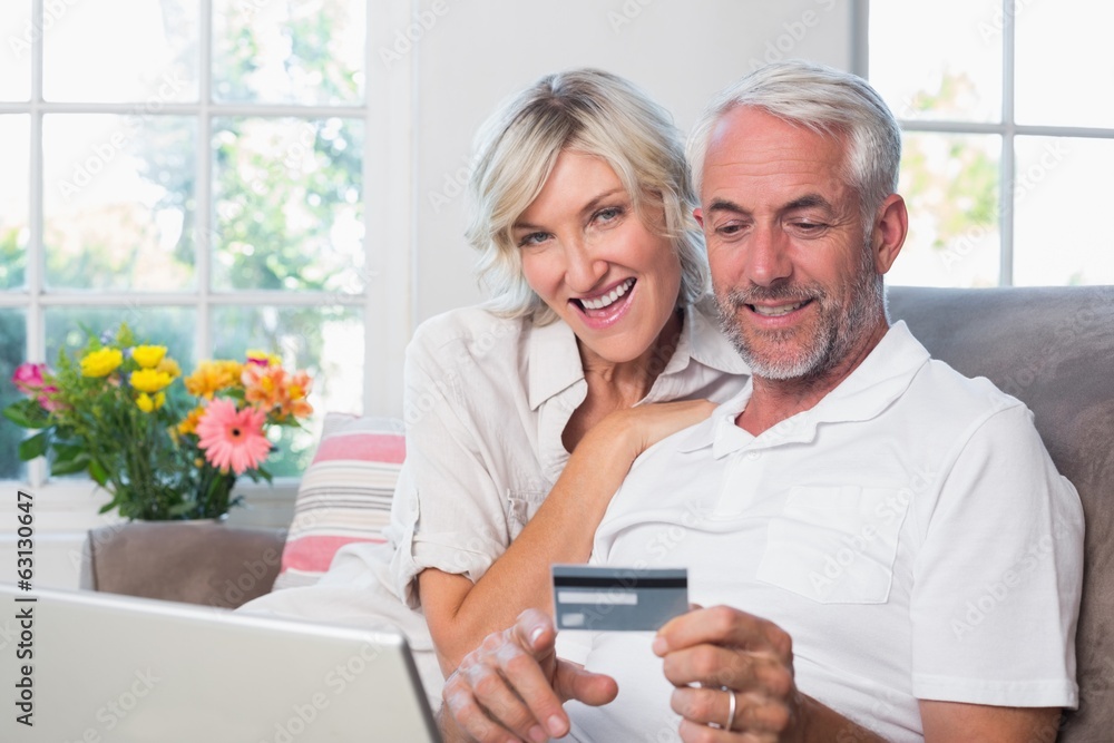 Happy mature couple doing online shopping at home