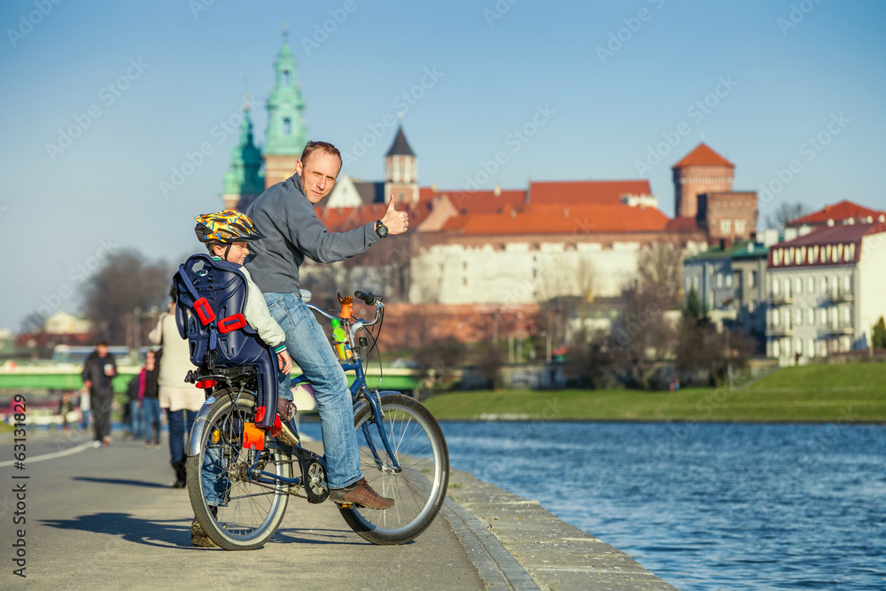 Fototapeta premium Walk on bike. Father with son cycling in city