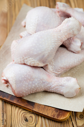 Close-up of raw chicken legs, wooden background, vertical shot