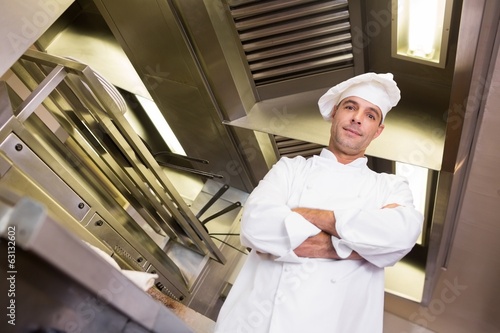 Smiling male cook with arms crossed in kitchen