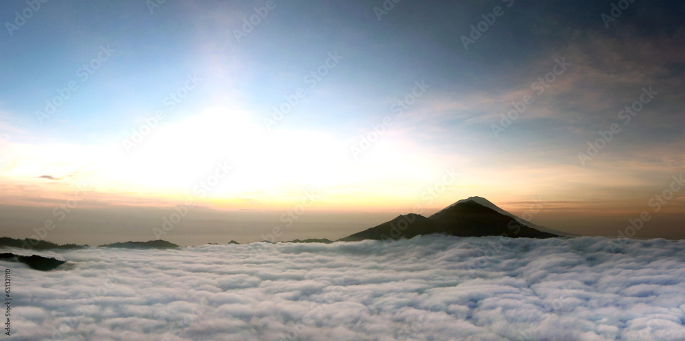 Sunrise above clouds with a mountain volcano view