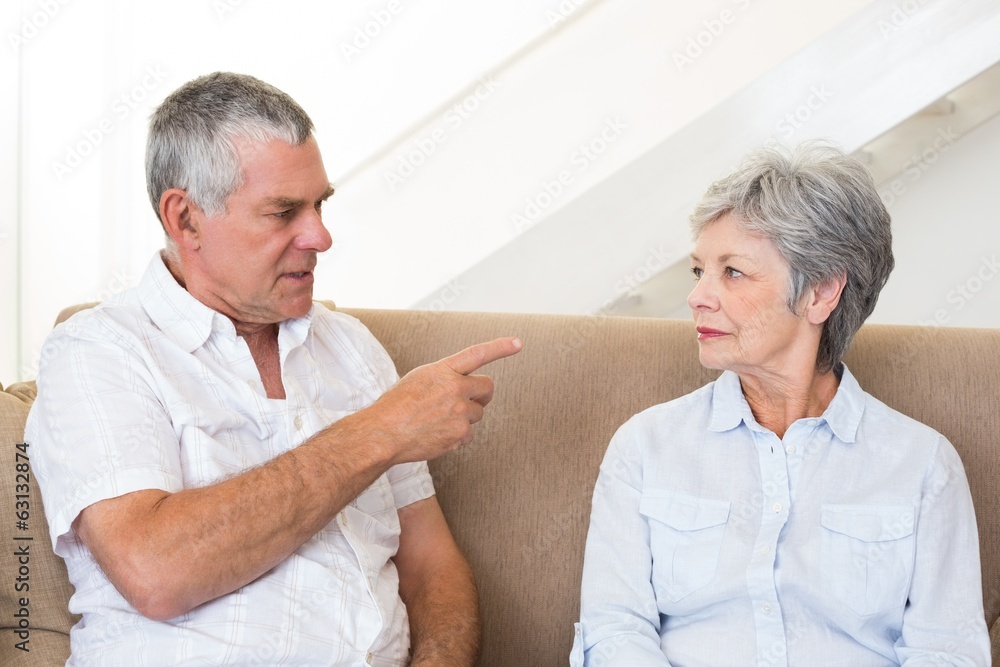 Senior couple sitting on couch having an argument Senior couple sitting on couch having an argument