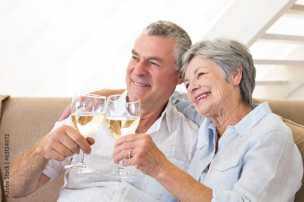 Senior couple sitting on couch having white wine Senior couple sitting on couch having white wine