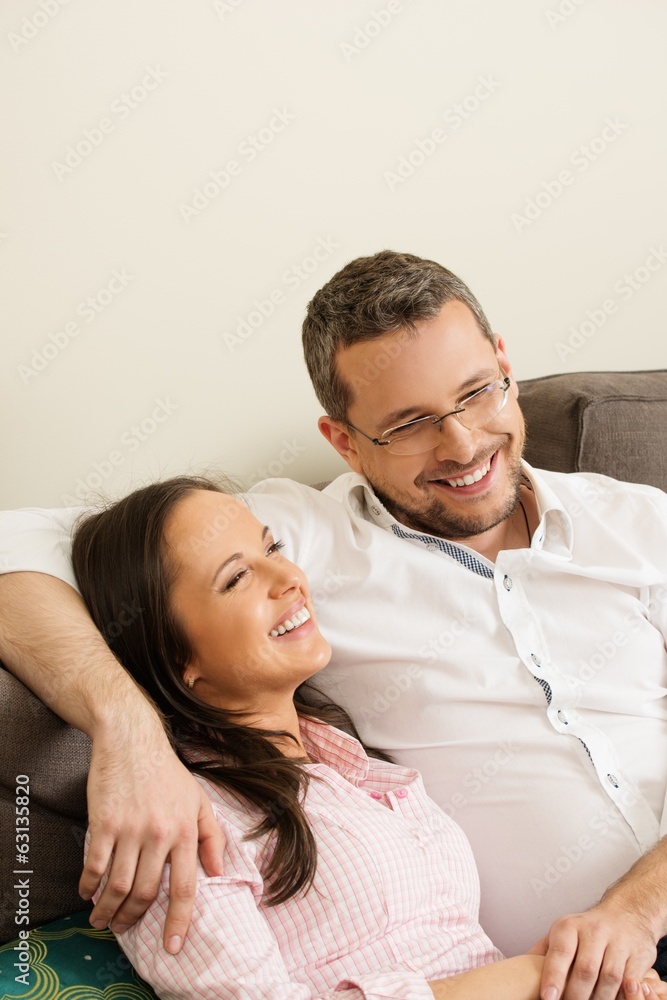 Young positive couple on a sofa in home interior Young positive couple on a sofa in home interior