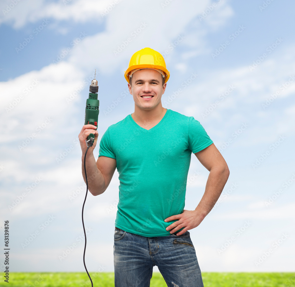 smiling manual worker in helmet with drill machine