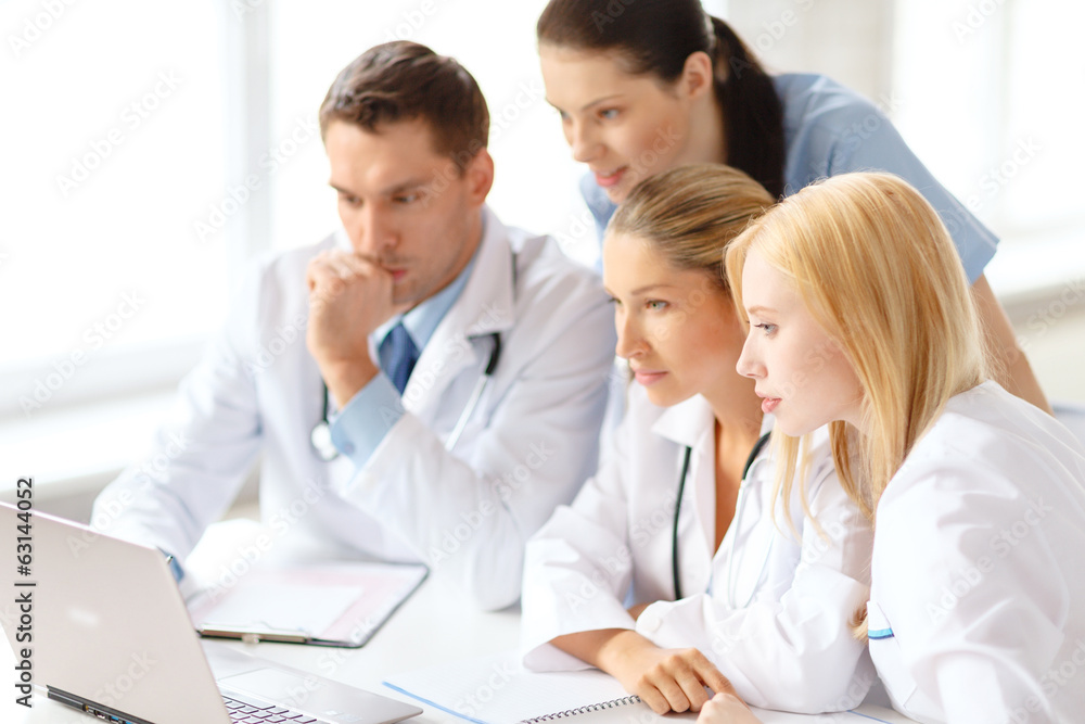 busy group of doctors looking at laptop computer busy group of doctors looking at laptop computer