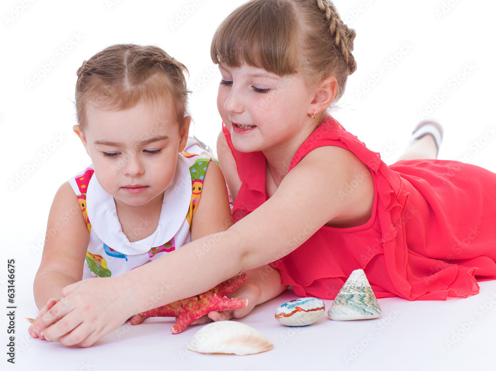two little girls are playing and shells and starfish. two little girls are playing and shells and starfish.