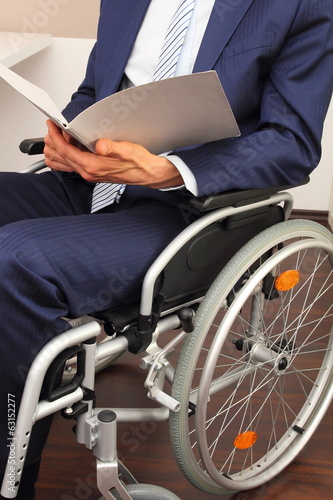 Geschaeftsmann im Rollstuhl mit Dokument