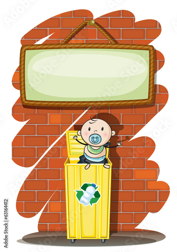 A trashcan with a baby below the hanging signboard