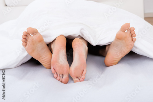 Low Section Of Intimate Couple Under Blanket