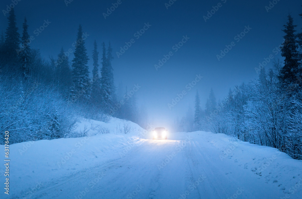Fototapeta premium lights of car and winter road in forest