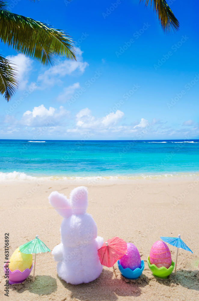 Easter bunny and color eggs on the beach