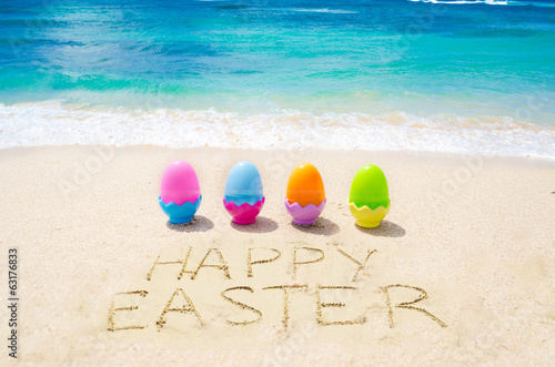 Sign "Happy Easter" with color eggs on the on the beach