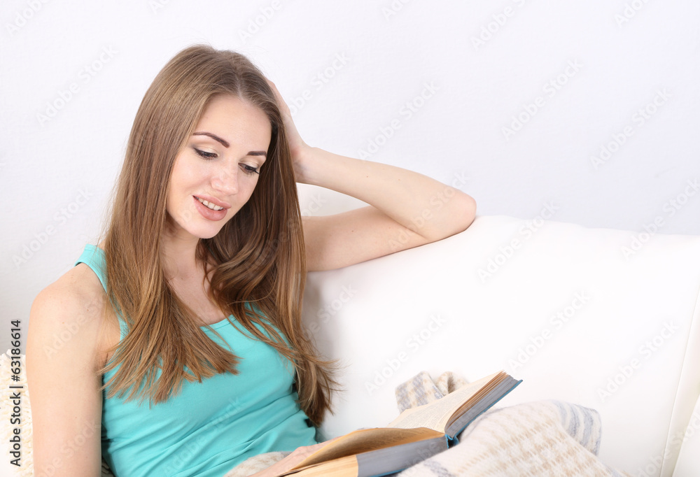Young woman resting with book on sofa at home Young woman resting with book on sofa at home