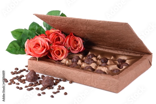 Delicious chocolates in box with flowers isolated on white